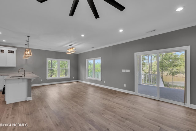 unfurnished living room with sink, crown molding, light hardwood / wood-style floors, and ceiling fan