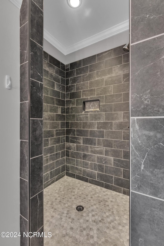 bathroom with crown molding and a tile shower