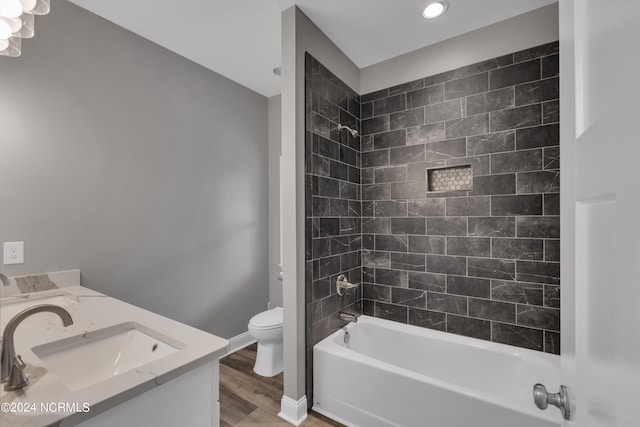 full bathroom with vanity, tiled shower / bath combo, toilet, and hardwood / wood-style flooring