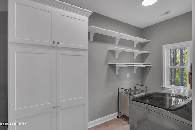 washroom with cabinets, separate washer and dryer, and light hardwood / wood-style floors