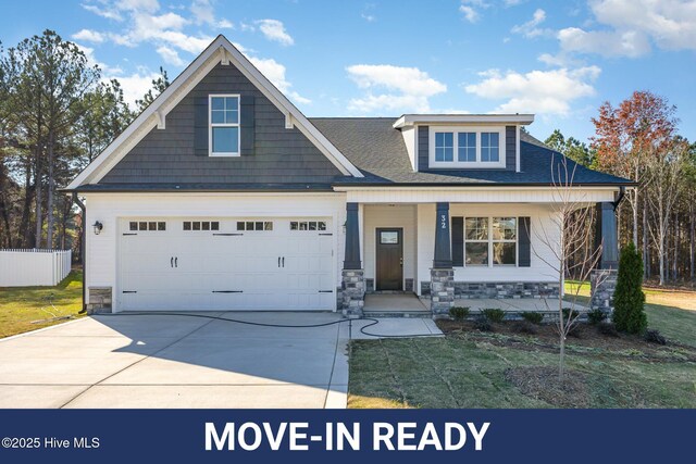 craftsman-style home with a garage, covered porch, and a front lawn