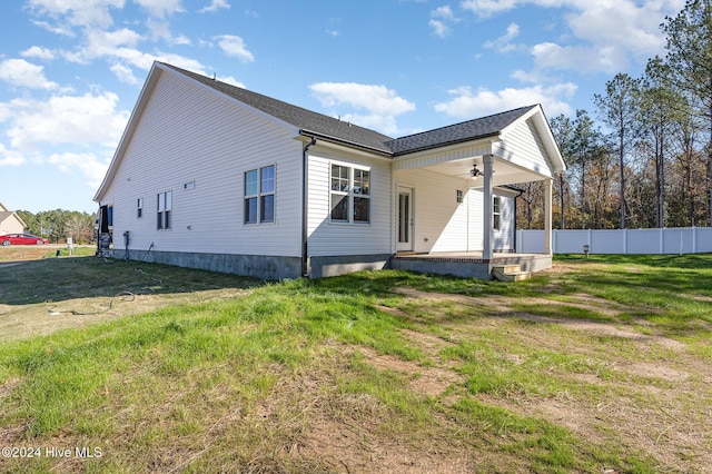 back of house featuring covered porch, ceiling fan, and a lawn