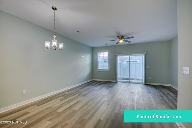 kitchen with hardwood / wood-style floors, light stone countertops, a notable chandelier, electric range oven, and white cabinetry