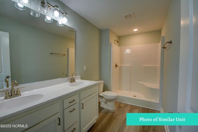 bathroom featuring walk in shower, vanity, wood-type flooring, and toilet