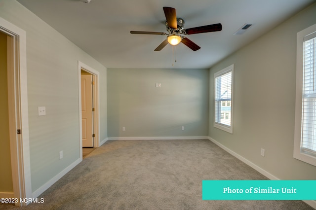 empty room with ceiling fan and light carpet