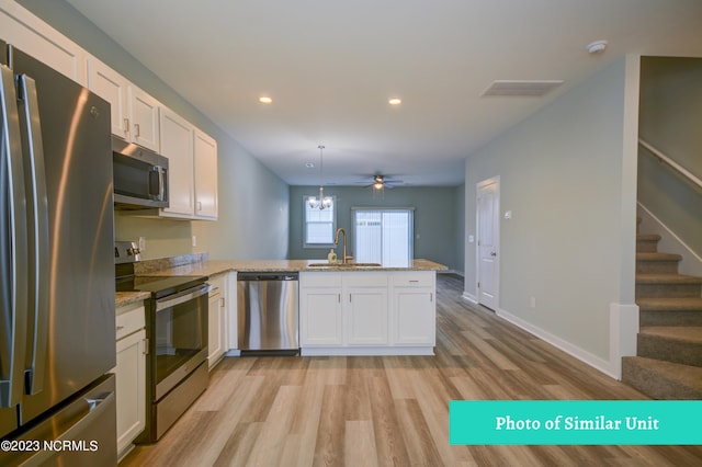 kitchen featuring pendant lighting, stainless steel appliances, kitchen peninsula, and white cabinets