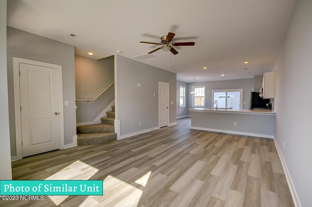 unfurnished living room with ceiling fan, light hardwood / wood-style floors, and sink