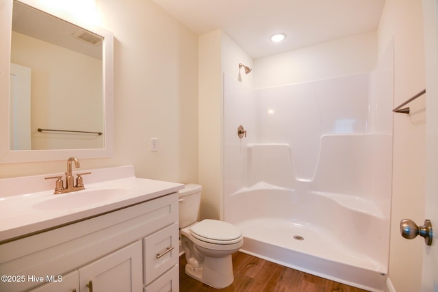 bathroom featuring wood-type flooring, toilet, vanity, and a shower