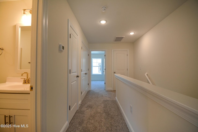 hall with sink and light carpet