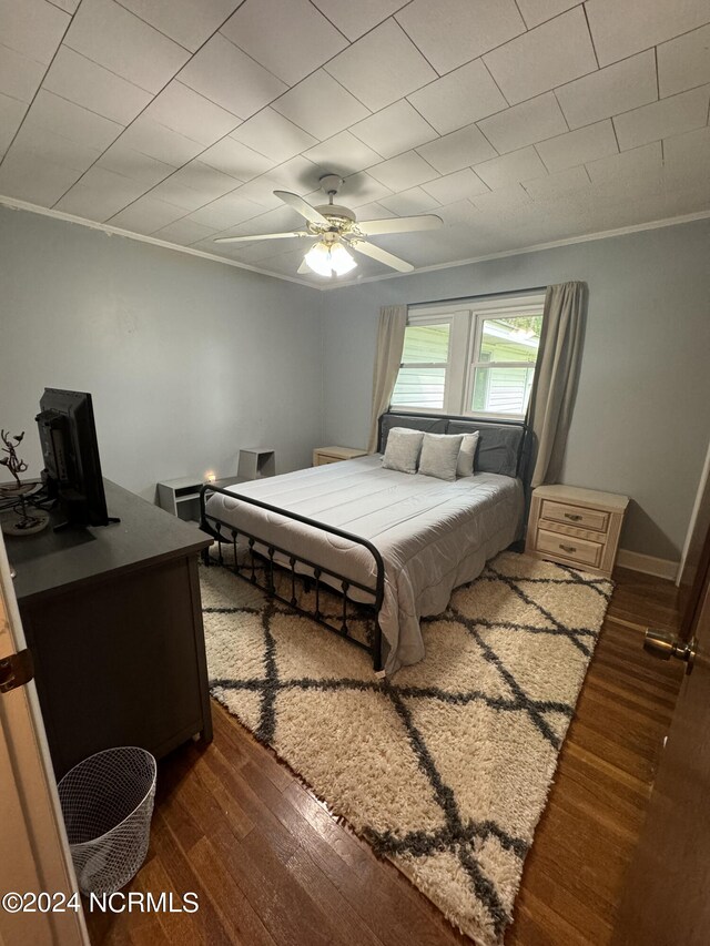 bedroom with hardwood / wood-style flooring, ornamental molding, and ceiling fan