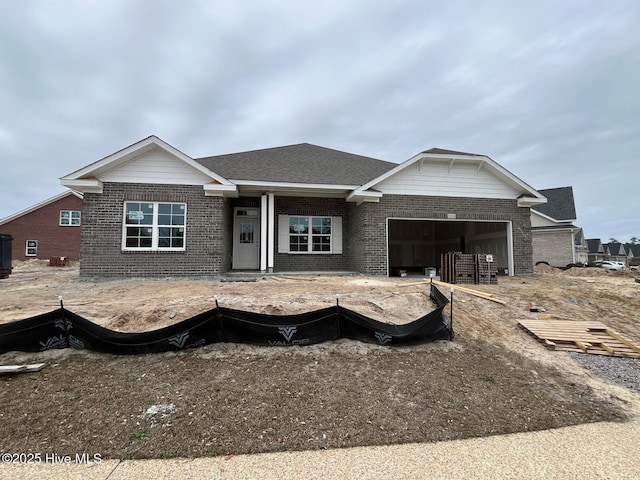 view of front of home featuring a garage, brick siding, and roof with shingles