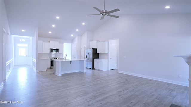 1254 Palatka Pl SE, Bolivia, NC 28422 - unfurnished living room with high vaulted ceiling, light wood-style floors, ceiling fan, baseboards, and recessed lighting