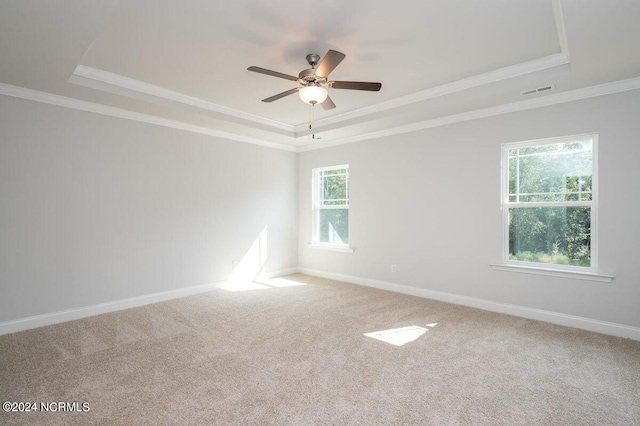 carpeted empty room featuring ornamental molding, a tray ceiling, and baseboards