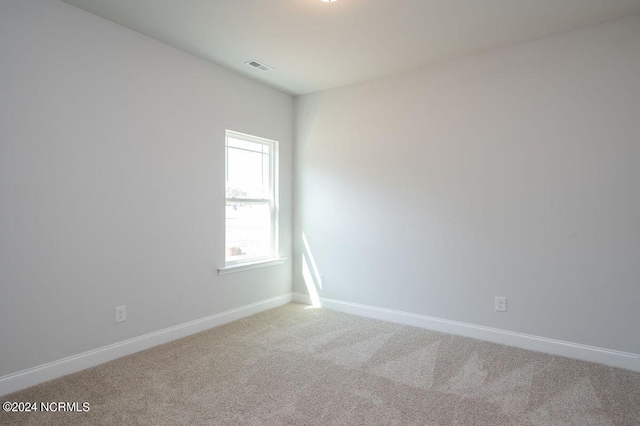 spare room with carpet floors, visible vents, and baseboards