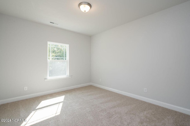 empty room featuring carpet, visible vents, and baseboards