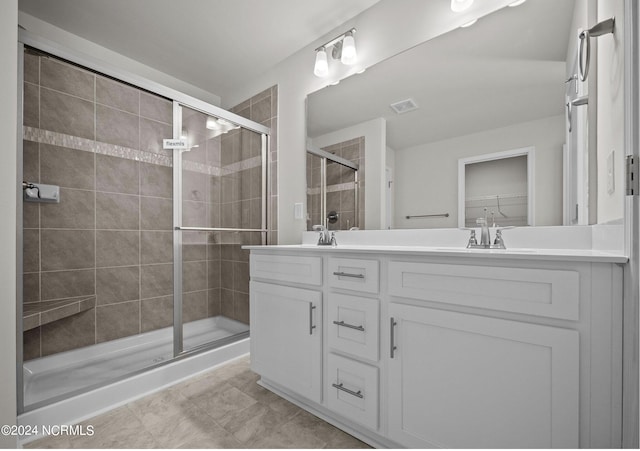 bathroom with a sink, visible vents, double vanity, a stall shower, and a walk in closet