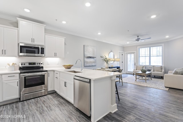 kitchen featuring stainless steel appliances, sink, a breakfast bar area, and white cabinets