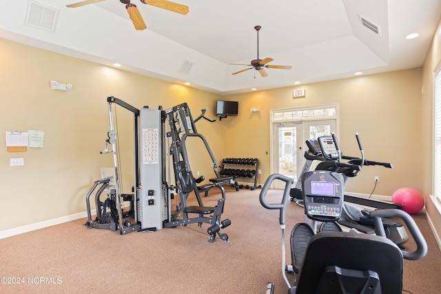 workout area featuring a raised ceiling, ceiling fan, and french doors