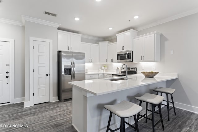 kitchen with appliances with stainless steel finishes, sink, a breakfast bar area, and white cabinets