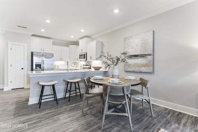 dining space featuring ornamental molding, dark wood-type flooring, and sink