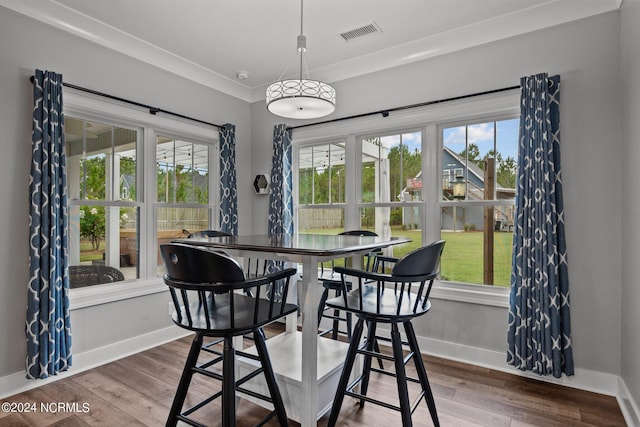 dining space with crown molding, hardwood / wood-style floors, and plenty of natural light