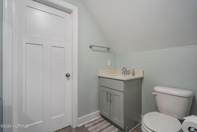 bathroom with vaulted ceiling, vanity, hardwood / wood-style flooring, and toilet