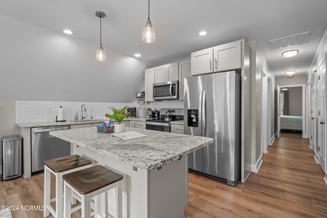 kitchen featuring decorative backsplash, a center island, wood-type flooring, and appliances with stainless steel finishes