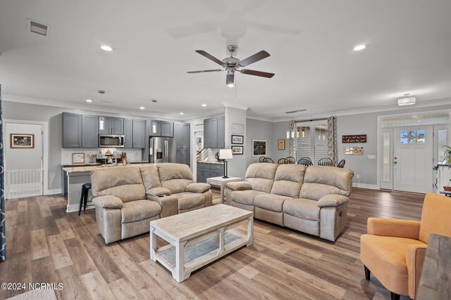 living room featuring light hardwood / wood-style flooring, ceiling fan, and crown molding