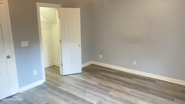 unfurnished bedroom with a walk in closet, a closet, and wood-type flooring