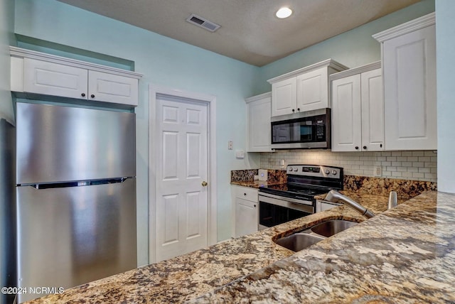 kitchen with white cabinetry, stainless steel appliances, and stone counters