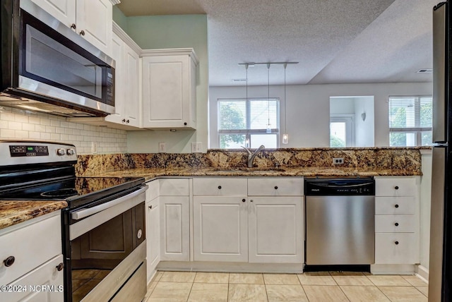 kitchen with tasteful backsplash, white cabinetry, sink, dark stone countertops, and stainless steel appliances