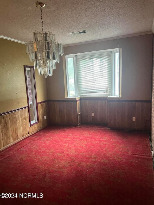 empty room with a textured ceiling, ornamental molding, and an inviting chandelier