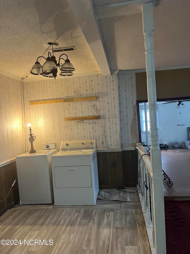 laundry area with wood-type flooring, wood walls, a textured ceiling, and washer and clothes dryer