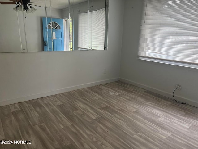 spare room with ceiling fan, hardwood / wood-style floors, and a wealth of natural light