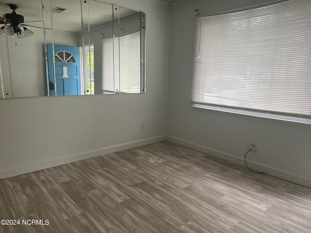 empty room with hardwood / wood-style flooring, ceiling fan, and a healthy amount of sunlight