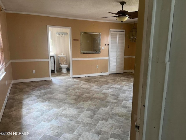 interior space with ceiling fan, a textured ceiling, and crown molding