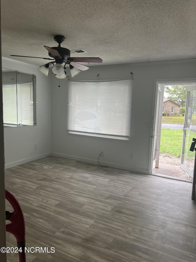 unfurnished room featuring ceiling fan, a healthy amount of sunlight, hardwood / wood-style floors, and a textured ceiling