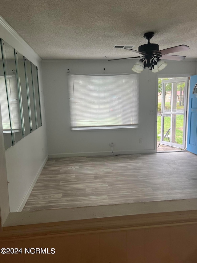 empty room featuring light wood-type flooring, ceiling fan, and a textured ceiling