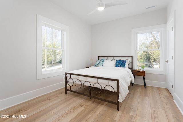 bedroom with ceiling fan, light wood-type flooring, and multiple windows