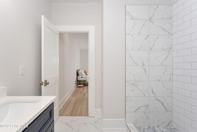 bathroom with a tile shower, vanity, and hardwood / wood-style flooring