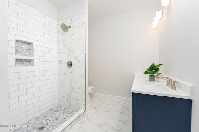 bathroom with a tile shower, vanity, and toilet