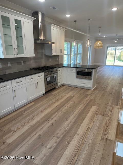 115 Seagate Pl, Wilmington, NC 28403 - kitchen featuring wall chimney range hood, stainless steel appliances, white cabinets, dark countertops, and recessed lighting