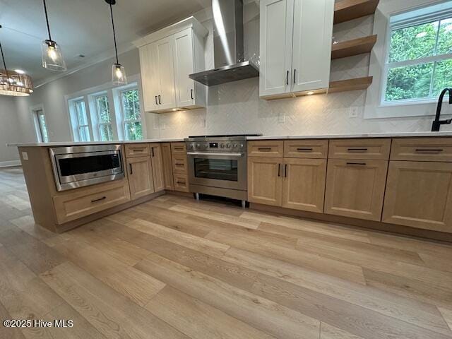 115 Seagate Pl, Wilmington, NC 28403 - kitchen featuring wall chimney range hood, stainless steel appliances, light wood-style flooring, a peninsula, and plenty of natural light