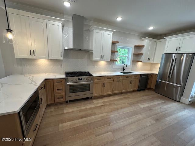 115 Seagate Pl, Wilmington, NC 28403 - kitchen with stainless steel appliances, wall chimney range hood, a sink, open shelves, and light wood-style floors