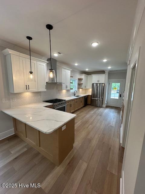 115 Seagate Pl, Wilmington, NC 28403 - kitchen with appliances with stainless steel finishes, wall chimney exhaust hood, a peninsula, light wood-style floors, and a sink