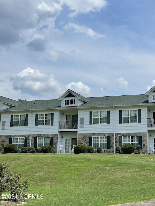 townhome / multi-family property with stone siding and a front yard