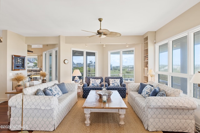 living room featuring wood-type flooring, built in features, and ceiling fan