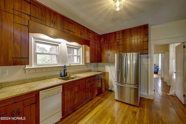 kitchen with light hardwood / wood-style flooring, sink, stainless steel fridge, and dishwasher