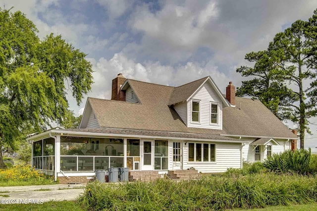 264 Main St, Swanquarter, NC 27885 - view of front of home with roof with shingles, a sunroom, and a chimney