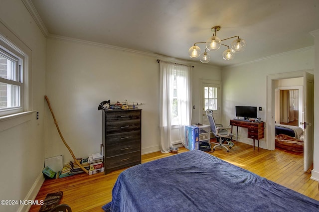 bedroom with hardwood / wood-style flooring, ornamental molding, and an inviting chandelier